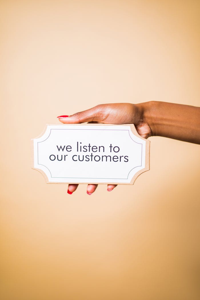 Crafting Captivating Headlines: Your awesome post title goes here A hand holding a sign saying 'we listen to our customers' on a neutral background.